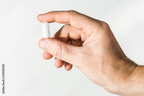 male hand holding a pill against white background