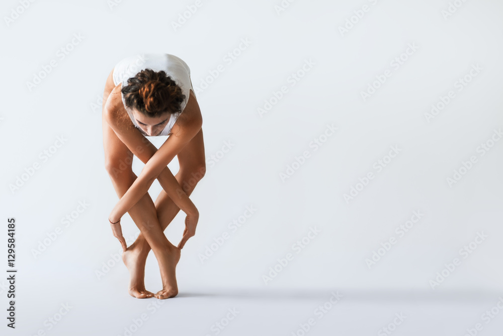 Fototapeta premium Young beautiful dancer posing on a studio background