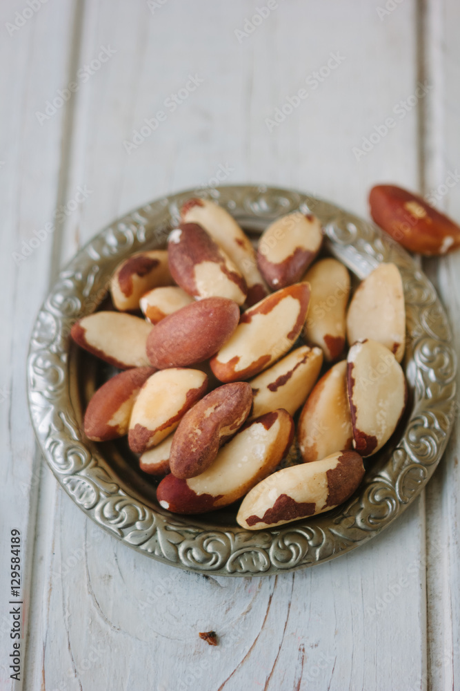 Brazil nuts in metal plate over the white wooden table. Brazil nuts in metal plate over the white wooden table.