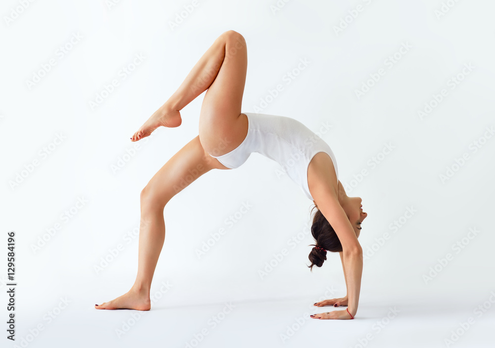 Young woman doing yoga asana bridge pose with right leg up