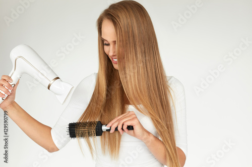 Hair Care. Woman Drying Beautiful Long Hair Using Dryer