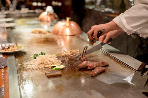 Quadro em tela Hand of Japanese chef cooking beef steak on hot pan, beef and vegetable