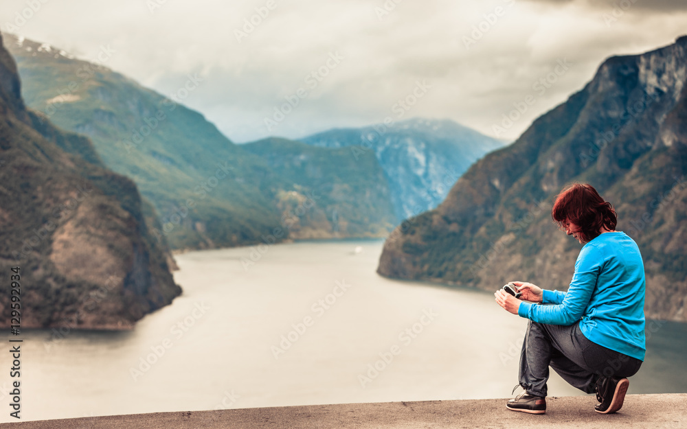 Female tourist taking photo at norwegian fjord