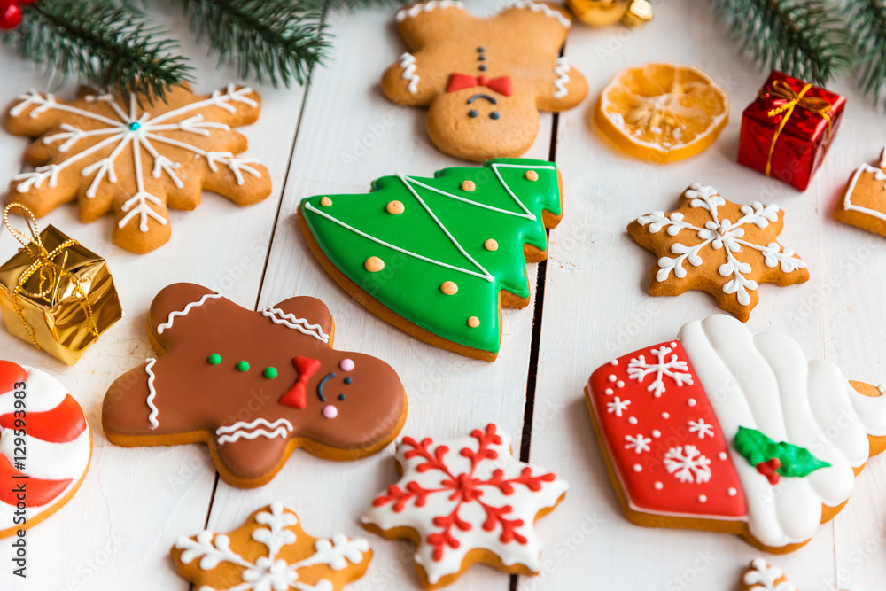 Obraz premium Christmas cookies with candy and festive branches fir. Homemade delicious Christmas gingerbread cookies on the wooden background.