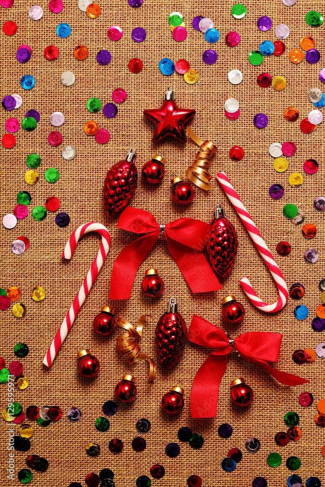 Collage of Christmas tree decorations, ribbons, candy on the background of burlap.