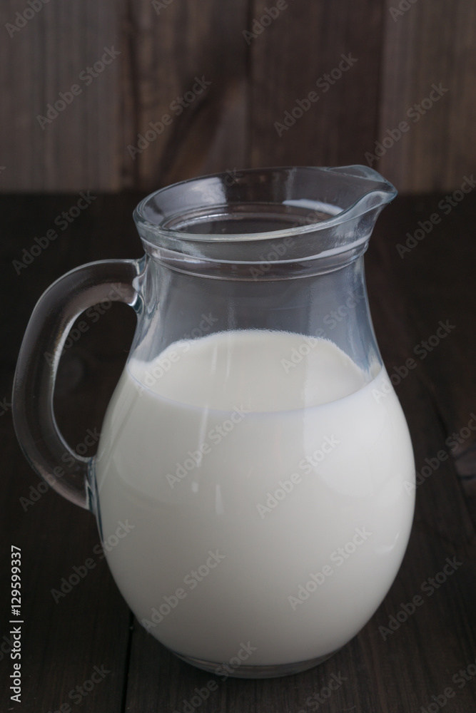 full jug of milk on dark wooden background