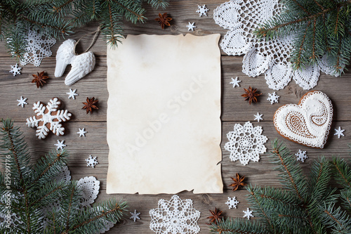 Christmas wooden background with branches of trees, lace snowflakes, gingerbread and blank greeting list