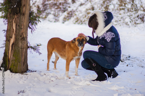 Girl stroking his dog near a tree