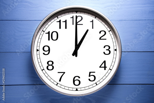 Round clock shows shows at 1 o'clock, clock on blue background