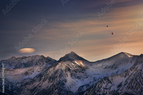 Balloons over the snowy mountain during sunset