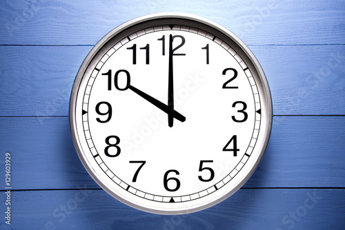 Round clock shows shows at 10 o'clock, clock on blue background