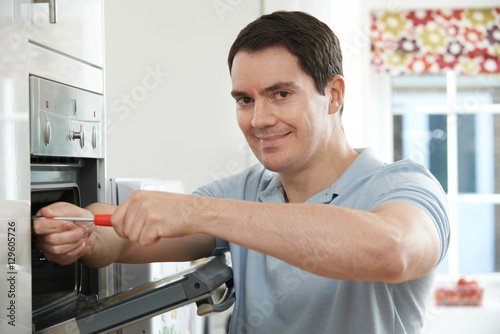 Repairman Fixing Domestic Oven In Kitchen