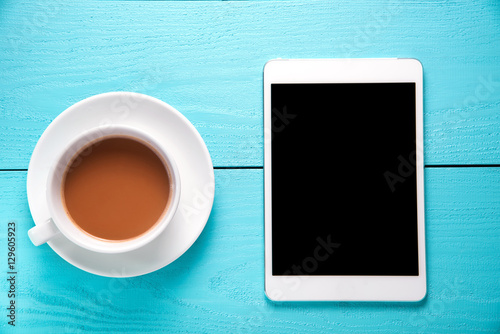 tablet and cup of tea on wooden table