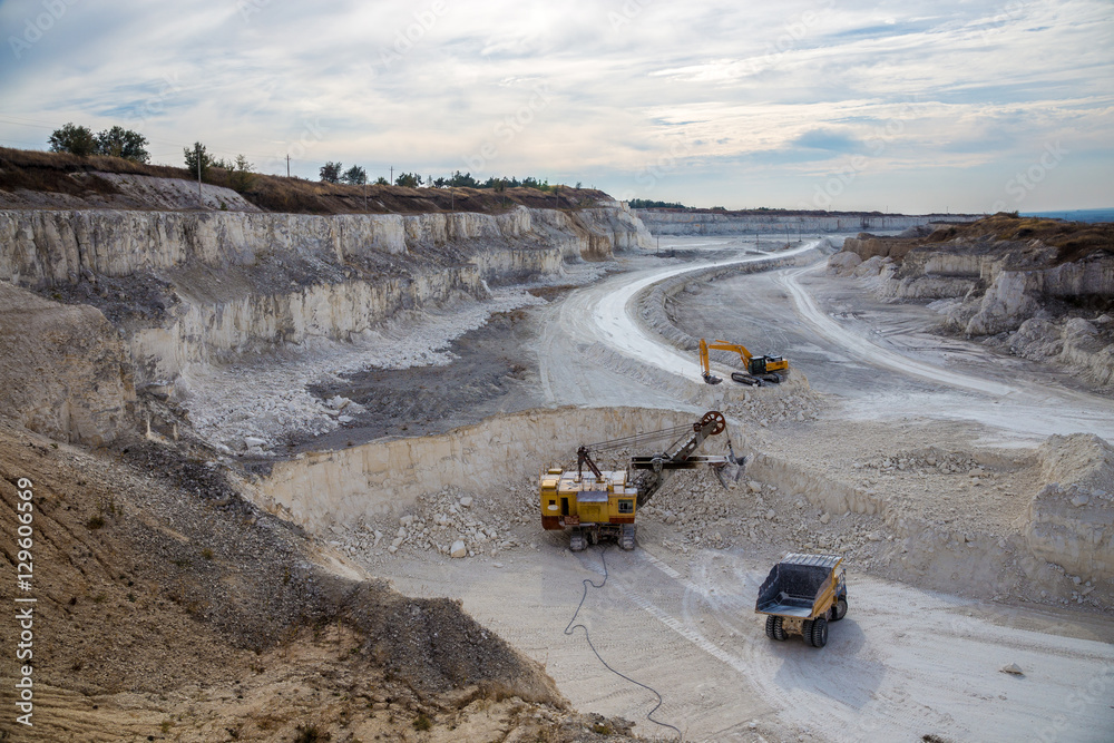 Excavators and dump trucks working and extracting the chalk in a quarry Excavators and dump trucks working and extracting the chalk in a quarry