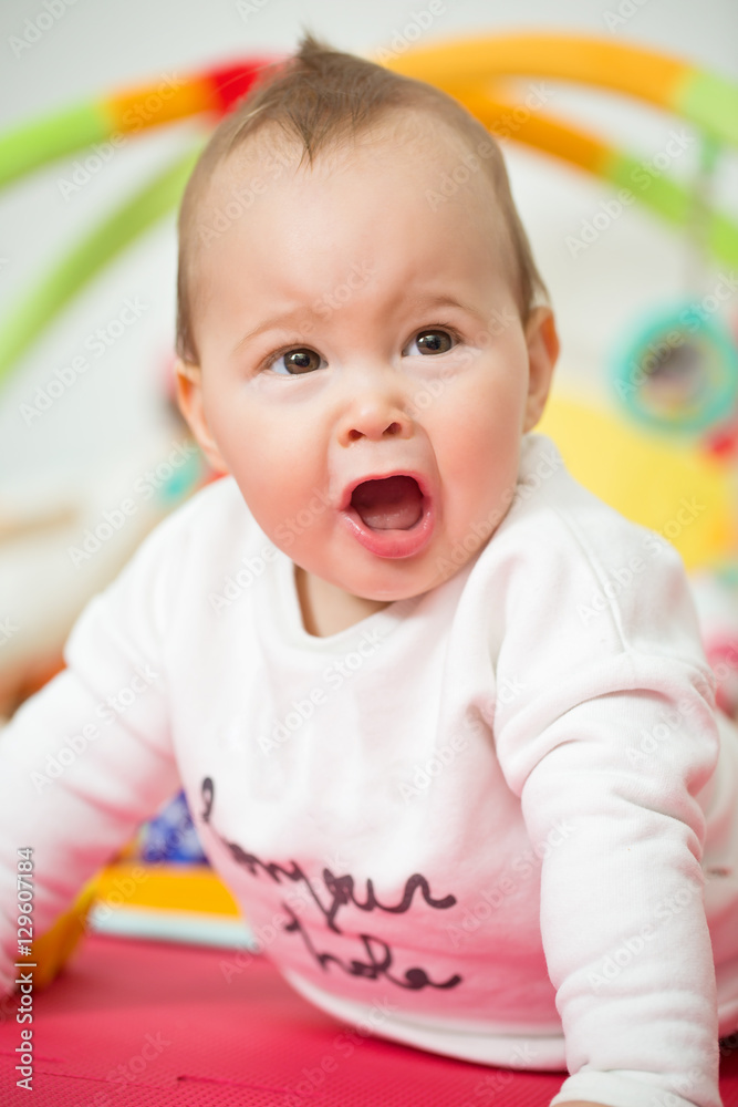Eight months old baby girl playing with colorful toys on a floor Eight months old baby girl playing with colorful toys on a floor