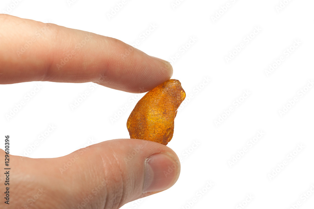 large piece of amber, between fingers on white background large piece of amber, between fingers on white background