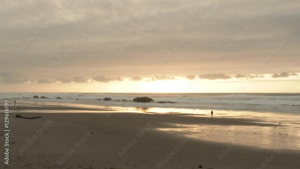 Wide angle beach scenic at the Oregon Coast with unreceognizable person walking during low tide sunset. Wide angle beach scenic at the Oregon Coast with unreceognizable person walking during low tide sunset.