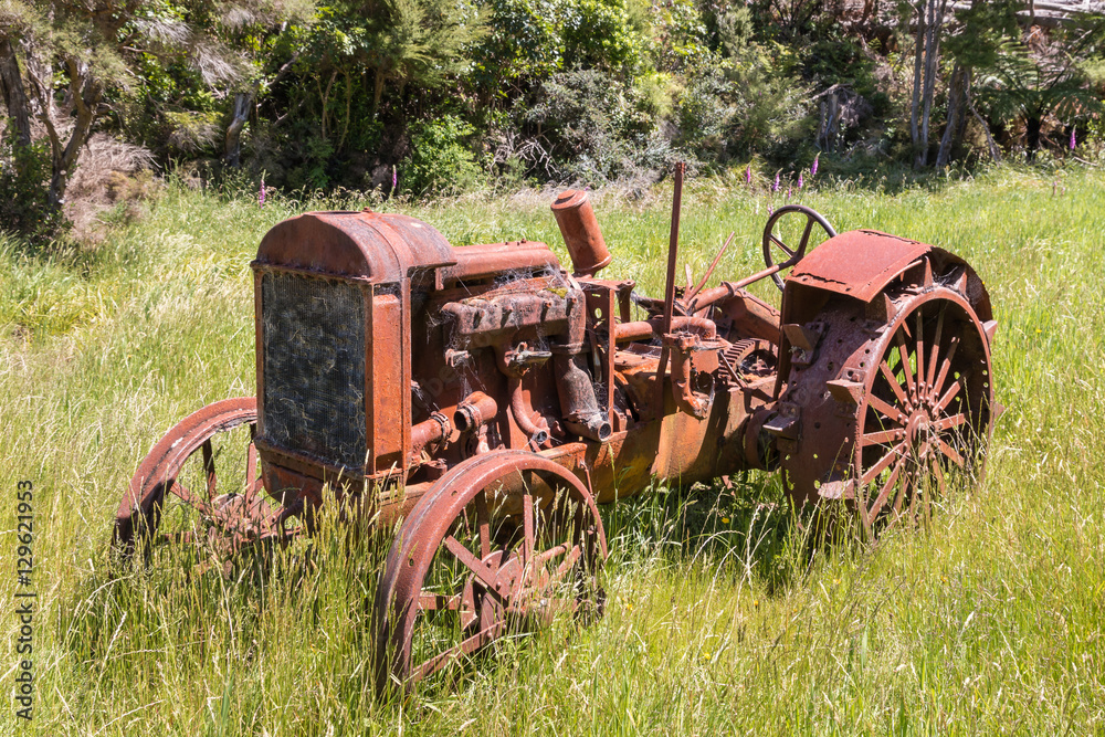 closeup of old rusty tractor in grass field closeup of old rusty tractor in grass field