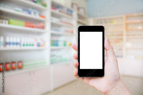 Pharmacy store with female holding mobile phone