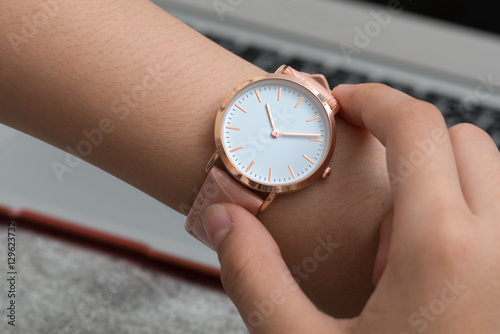 Wrist watch on girl's hand in front of a notebook computer