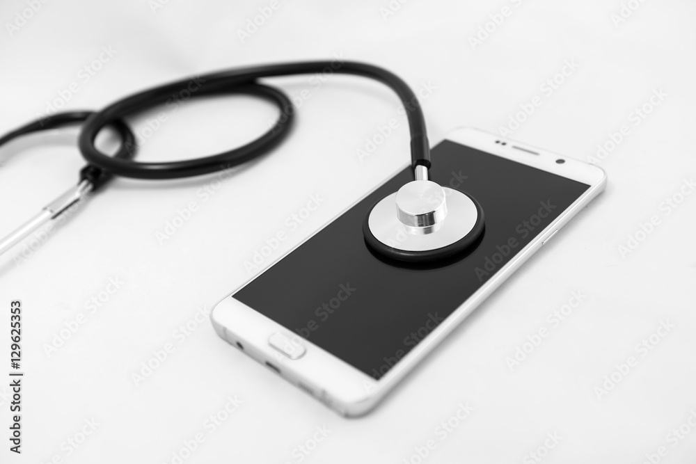 Medical stethoscope tool over the surface of a mobile smart phone, composition isolated over the white background Medical stethoscope tool over the surface of a mobile smart phone, composition isolated over the white background