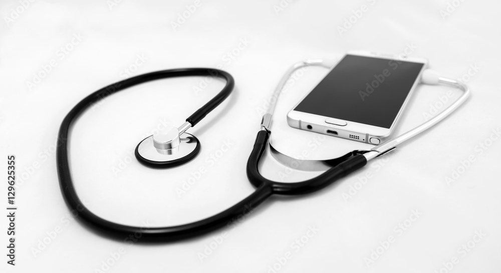Medical stethoscope tool over the surface of a mobile smart phone, composition isolated over the white background. with Selective Focus Medical stethoscope tool over the surface of a mobile smart phone, composition isolated over the white background. with Selective Focus