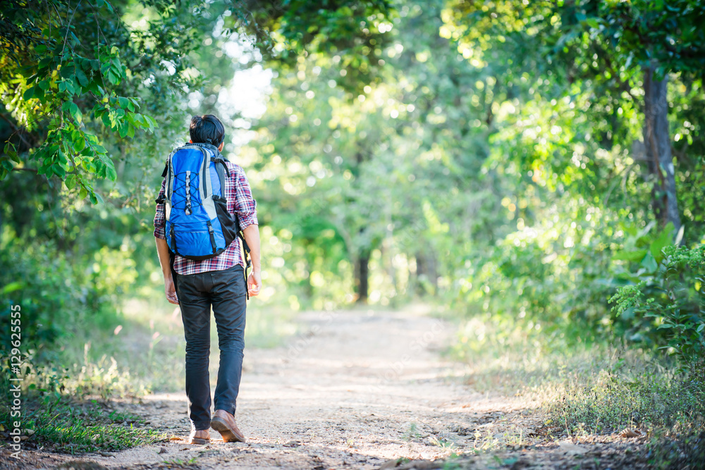 Young hipster man walking on the rural road during hikes on vaca Young hipster man walking on the rural road during hikes on vaca