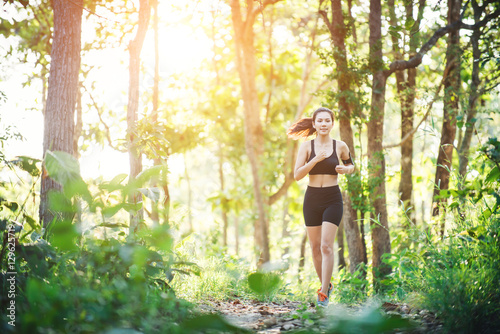 Young woman jogging on rural road in green forest nature. © Johnstocker