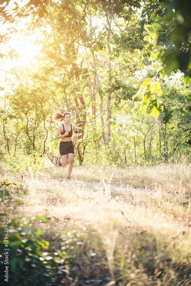 Young woman jogging on rural road in forest nature. Young woman jogging on rural road in forest nature.