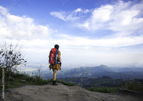 Hiker woman look binoculars on the mountain, background blue sky, Thailand