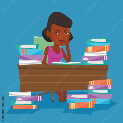 Student sitting at the table with piles of books.