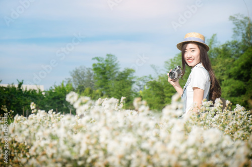 Asian hipster cute teen girl with camera in white flower garden,