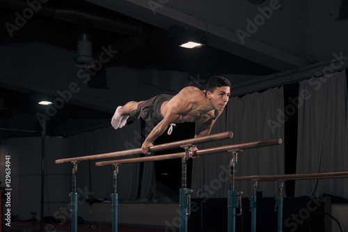 man gymanst in air, parallel bars