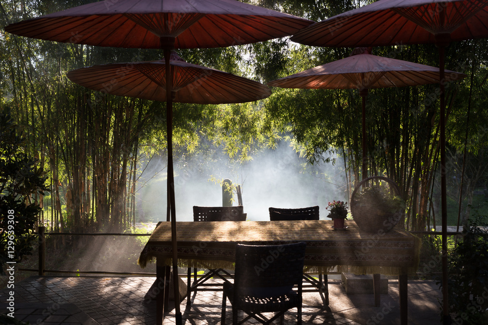 Fototapeta premium table and chair and red umbrella at patio with light ray through