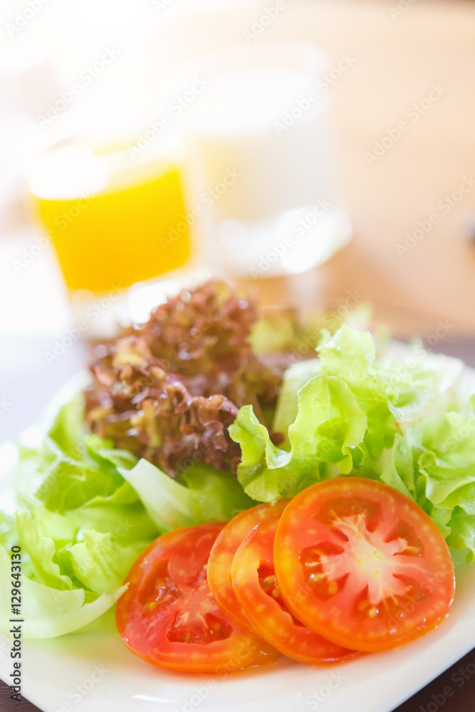 Fresh vegetable salad in ceramic plate on wood table and orange juice hot milk background with sunlight. Fresh vegetable salad in ceramic plate on wood table and orange juice hot milk background with sunlight.