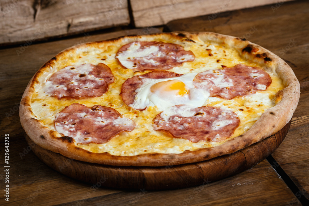 Pizza with ham and egg on wood background