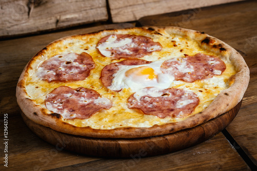 Pizza with ham and egg on wood background
