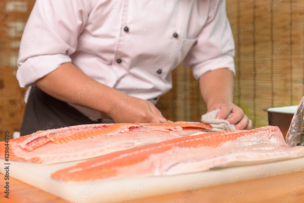 Japanese Chef preparing a fresh salmon on a cutting board 