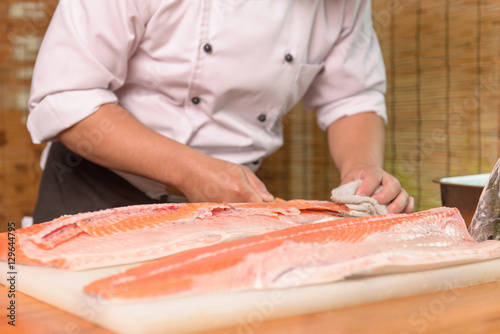 Japanese Chef preparing a fresh salmon on a cutting board 