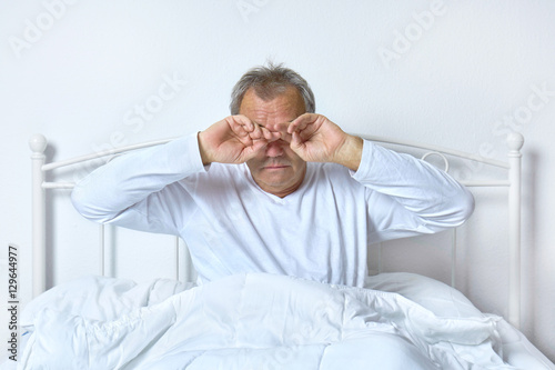 Senior im Bett im Schlafzimmer beim Aufwachen photo