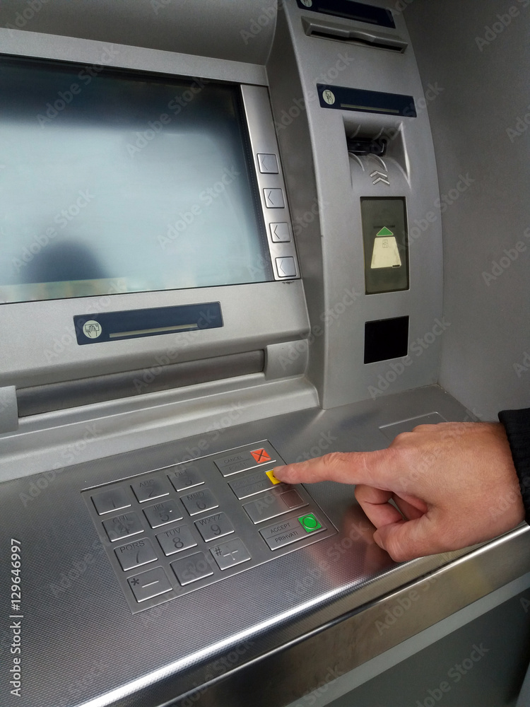 Man's using the ATM machine with cash cards and entering PIN/pass code on keypad. Man's using the ATM machine with cash cards and entering PIN/pass code on keypad.