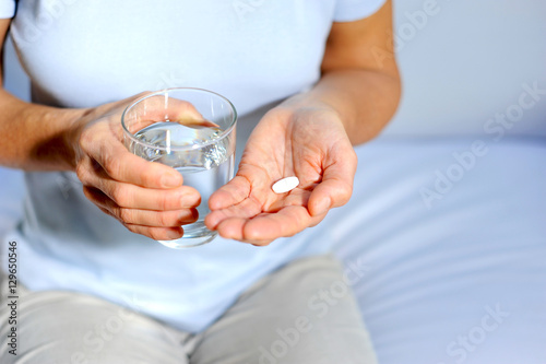 Frau nimmt Tablette gegen Schmerzen mit einem Glas Wasser ein photo