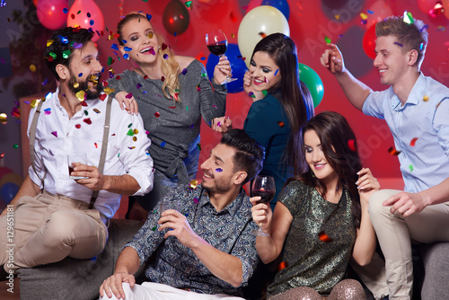 Couples enjoying party with drinks among colorful confetti