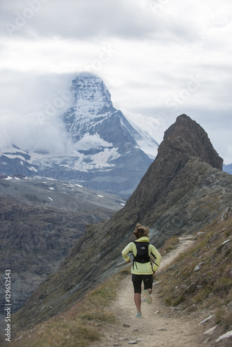 Running a trail in the Swiss Alps near Zermatt with a view of The Matterhorn in the distance, Zermatt, Valais photo