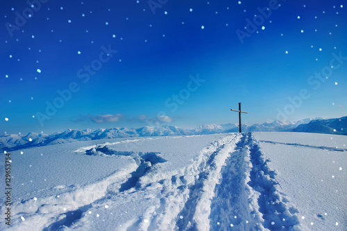 verschneiter Gipfel mit Gipfelkreuz in der Winternacht - blauer