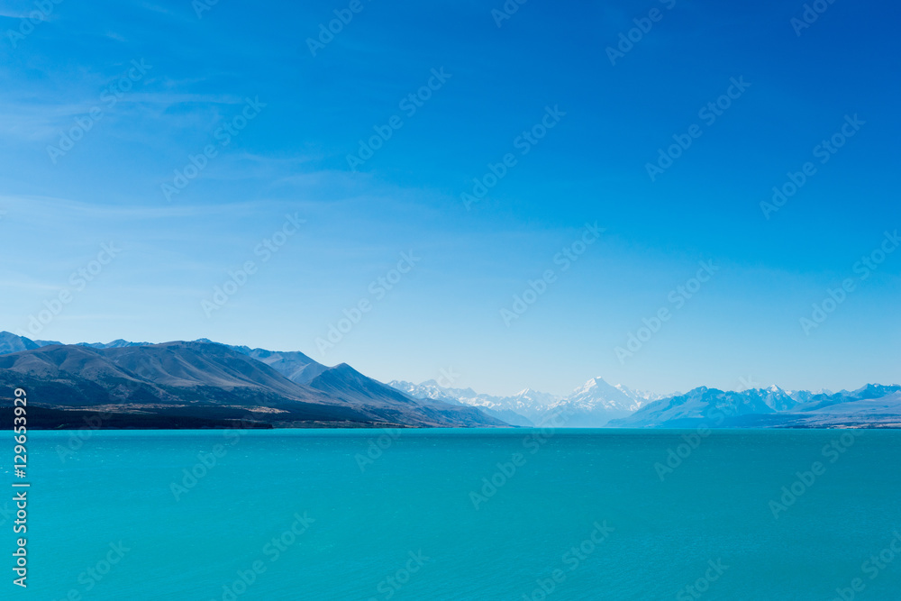 A turquoise blue lake with snow covered mountains in the distance, South Island, New Zealand A turquoise blue lake with snow covered mountains in the distance, South Island, New Zealand