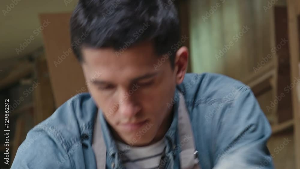 Tilt down and tilt up of concentrated male carpenter shaping wood plank with hand plane