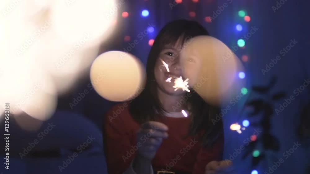 Young smiling happy girl having fun with sparklers before coloured lights background Young smiling happy girl having fun with sparklers before coloured lights background