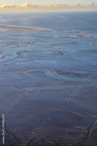 aerial view of the mudflat coastline at low tide with water winding in the mud and sand bank  Frisian island Ameland  The Netherlands