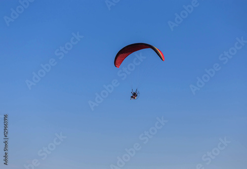 paraglider flying with paramotor on blue sky background